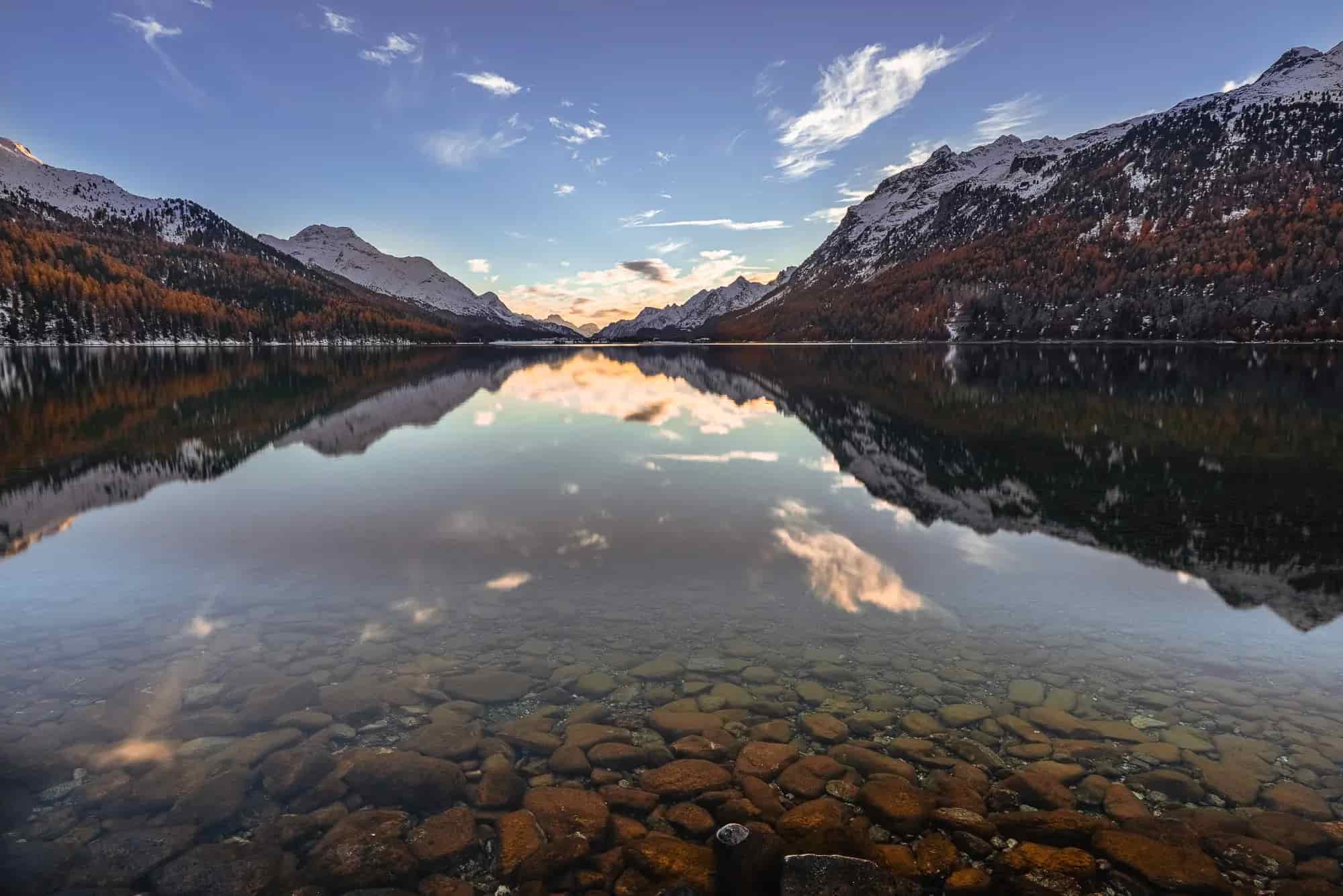 An interesting foreground leads into the reflection of the Silvaplana lake, the mountain slopes are decorated with larches and the whole motif runs towards the light atmosphere at the intersection of the valley